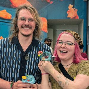 Two participants smile while holding their chosen Setting Seed sculptures during McNay Family Day at the McNay Art Museum.