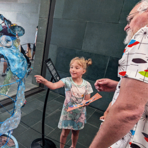 A child points toward Margaret Craig's Setting Seed installation while learning about the artwork.