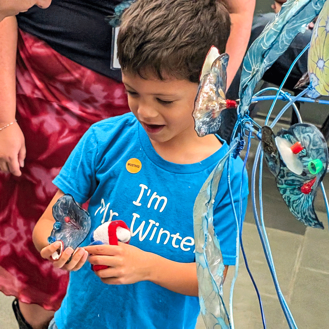 A young participant holds one of Margaret Craig's Setting Seed sculptures while exploring the installation.