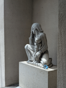 One of Margaret Craig's Setting Seed sculptures rests at the base of Charles Umlauf's War Mother (1939) at the McNay Art Museum in San Antonio, showing the relationship between the contemporary artwork and the historic sculpture.