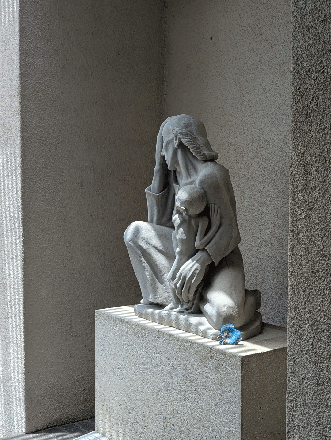One of Margaret Craig's Setting Seed sculptures rests at the base of Charles Umlauf's War Mother (1939) at the McNay Art Museum in San Antonio, showing the relationship between the contemporary artwork and the historic sculpture.